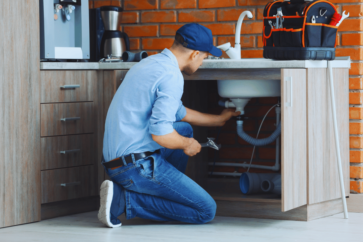plumber kneeling and working on a bathroom vanity sink